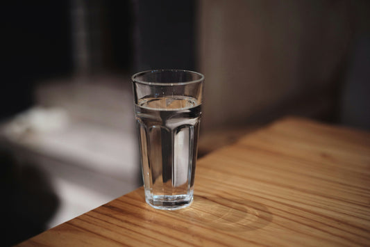 A clear glass of water on a wooden table symbolizing hydration – AquaNest